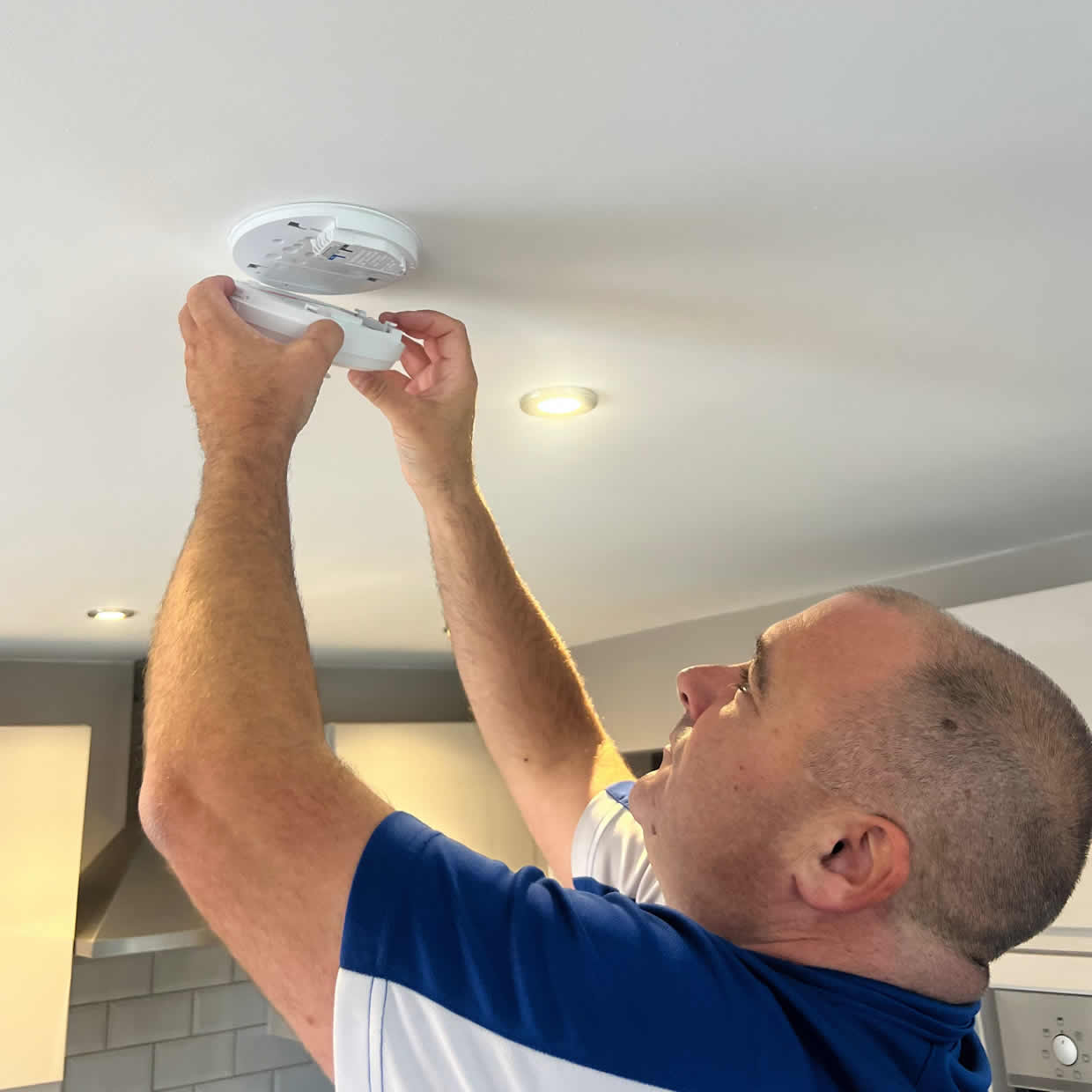 Smoke alarm installer fitting an alarm in an Ipswich property